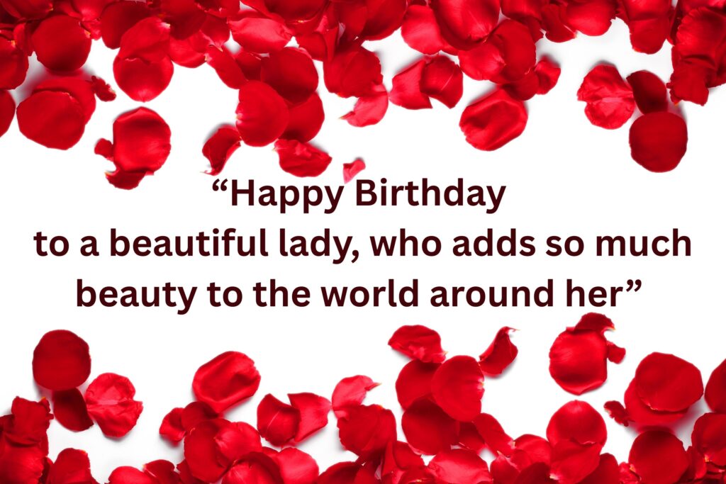 Elegant birthday greeting card with scattered red rose petals framing the top and bottom edges on a white background. In the center, a heartfelt message in bold dark red serif font reads: ‘Happy Birthday to a beautiful lady, who adds so much beauty to the world around her.’ The design combines romance, elegance, and warmth, making it ideal for a feminine birthday celebration.
