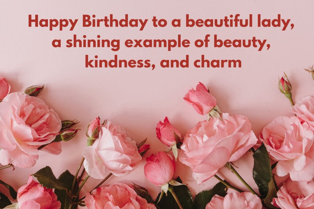 Beautiful birthday greeting card with soft pink roses and rosebuds arranged along the bottom edge on a pastel pink background. At the top, in bold red font, the message reads: ‘Happy Birthday to a beautiful lady, a shining example of beauty, kindness, and charm.’ The design radiates elegance, femininity, and warmth, making it perfect for wishing a graceful woman on her special day