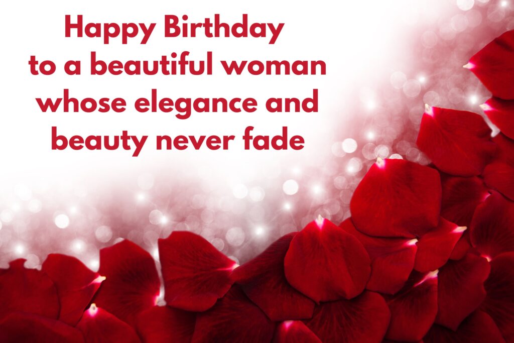 Romantic happy birthday greeting card with deep red rose petals scattered across the bottom and right side, blending into a glowing white background with sparkling bokeh lights. In bold red lettering, the message reads: ‘Happy Birthday to a beautiful woman whose elegance and beauty never fade.’ The design conveys love, elegance, and celebration, making it ideal for a feminine birthday wish