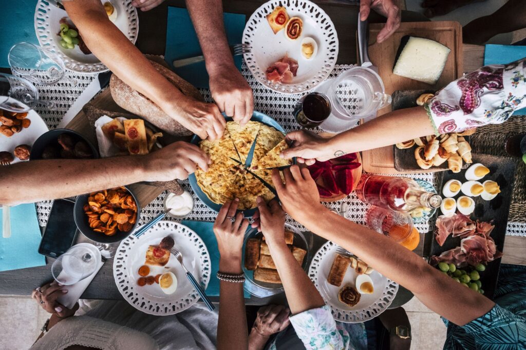 Overhead view of friends sharing tapas and finger foods around a vibrant picnic table—perfect for group gatherings, outdoor feasts, and Mediterranean-style picnic party ideas.